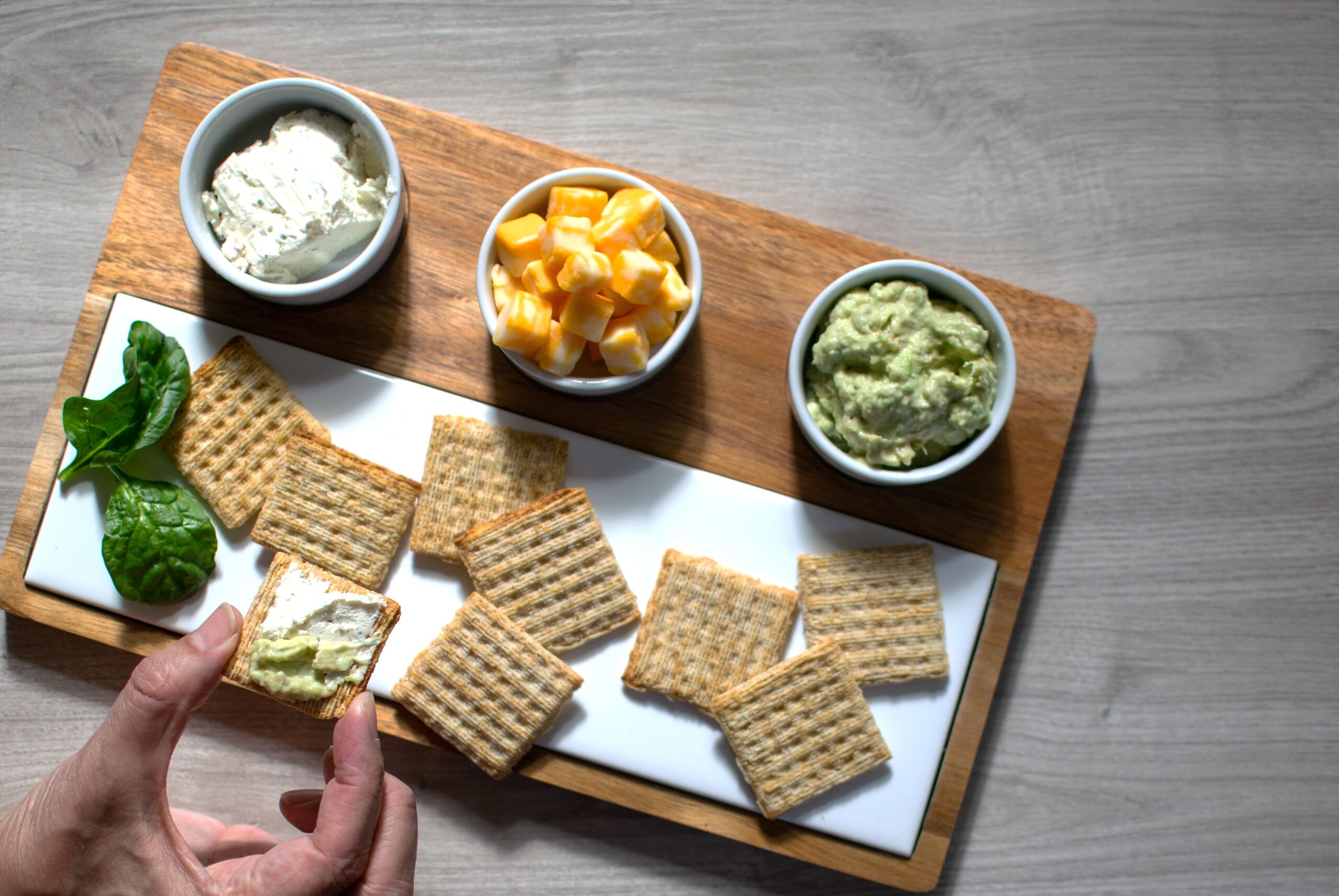 A person holding crackers and cheese mid-snack, emphasizing convenient and realistic IBS-friendly snacking in daily lif