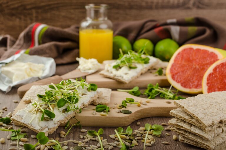 A rustic wooden table with real whole-food snacks like eggs, nuts, fruit, and cheese, emphasizing satisfying low FODMAP snack options that feel like normal food