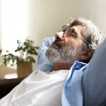 An adult resting quietly on a couch during recovery, reflecting the prolonged digestive sensitivity that can follow gastrointestinal infection