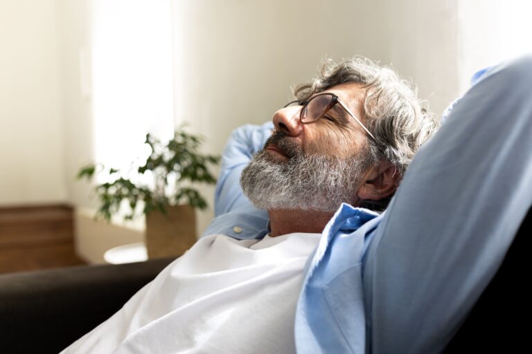 An adult resting quietly on a couch during recovery, reflecting the prolonged digestive sensitivity that can follow gastrointestinal infection